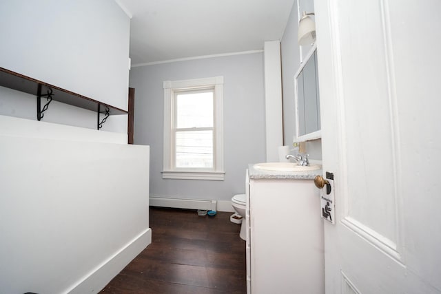 half bath featuring vanity, wood finished floors, baseboards, a baseboard radiator, and toilet