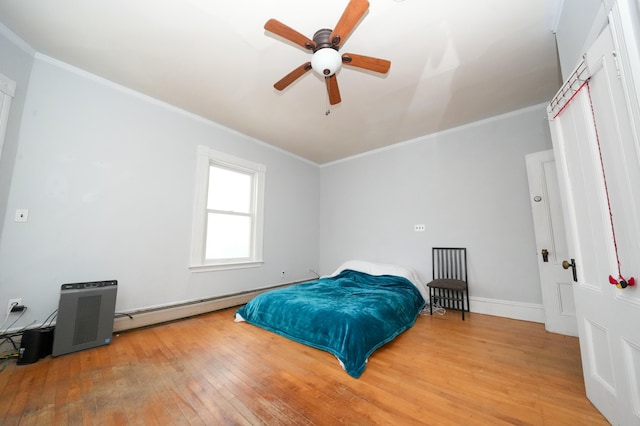 bedroom with baseboards, baseboard heating, light wood-style flooring, and crown molding