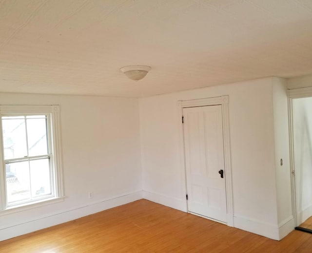 spare room featuring light wood-style floors and baseboards