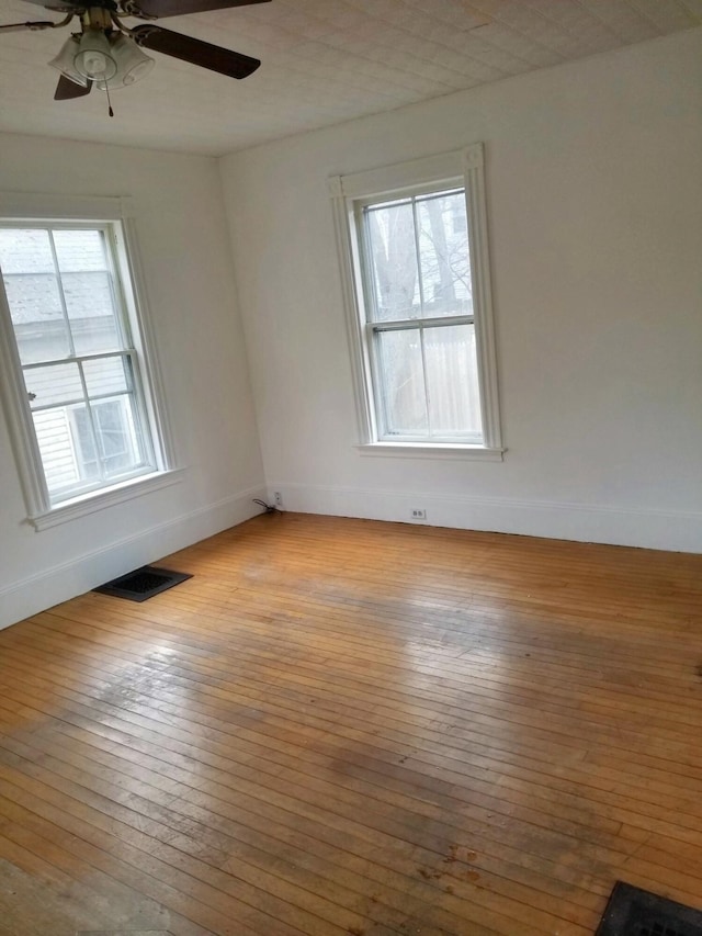 unfurnished room with baseboards, visible vents, and wood-type flooring