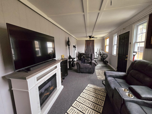 living area with a wealth of natural light, a glass covered fireplace, dark carpet, and ceiling fan