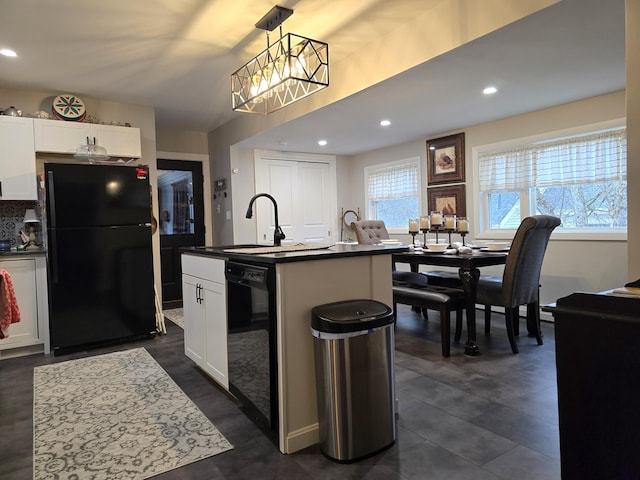 kitchen with black appliances, a kitchen island with sink, a sink, dark countertops, and white cabinets