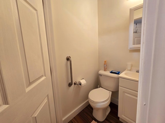 half bathroom with baseboards, toilet, wood finished floors, and vanity