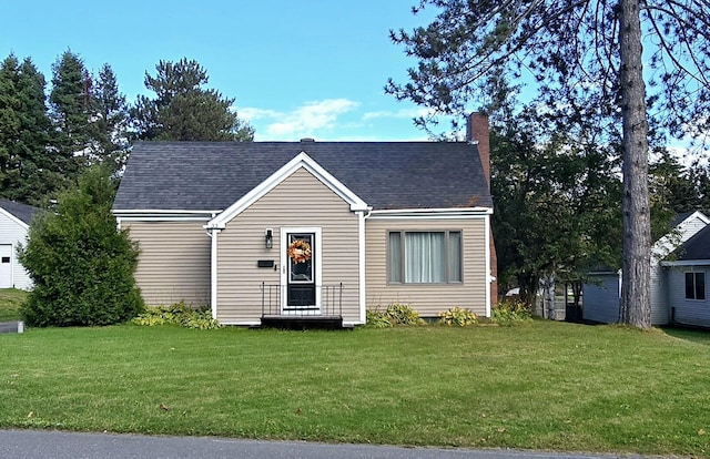 view of front facade with a chimney, a front yard, and roof with shingles