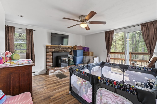 8 Royal Coachman Way, Shapleigh, ME 04076 - bedroom with a baseboard heating unit, a wood stove, wood finished floors, ceiling fan, and baseboards