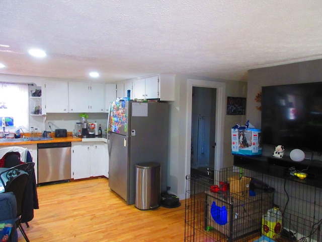 kitchen with light wood-type flooring, stainless steel appliances, light countertops, and white cabinetry