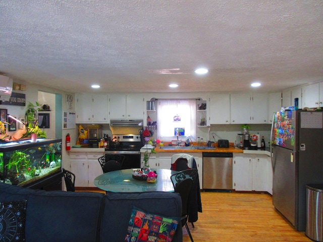 kitchen featuring light wood-style flooring, under cabinet range hood, open shelves, white cabinetry, and stainless steel appliances