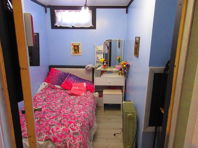 bedroom with radiator and wood finished floors