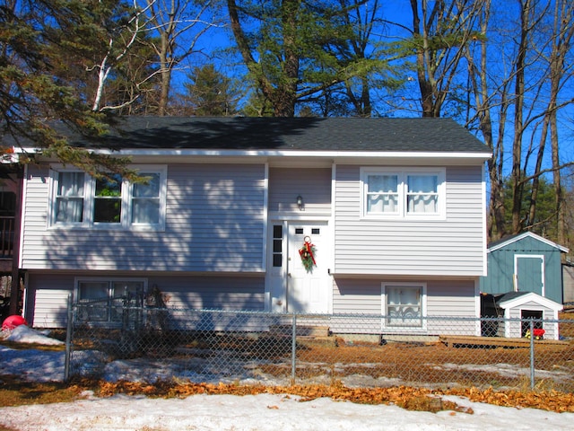 bi-level home featuring an outdoor structure, a shed, and a fenced front yard