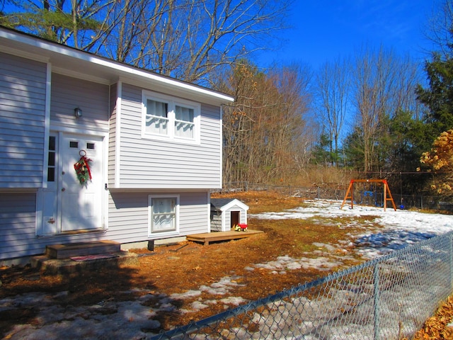 view of side of home with entry steps, a playground, and fence