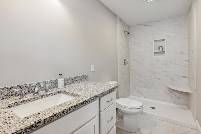 full bathroom with vanity, toilet, marble finish floor, and tiled shower