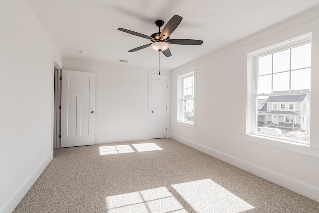 carpeted empty room with visible vents, baseboards, and ceiling fan