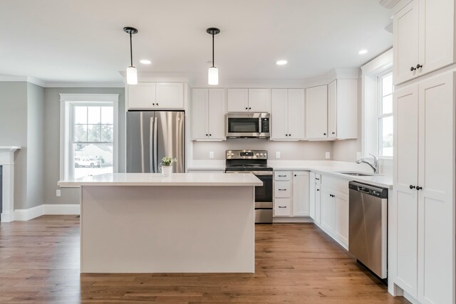 kitchen with white cabinets, light wood-type flooring, appliances with stainless steel finishes, and a sink