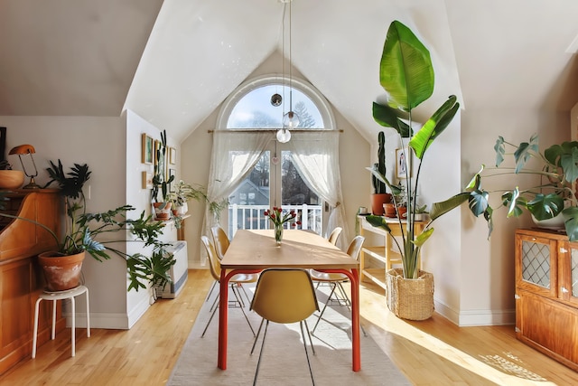 dining room with vaulted ceiling, baseboards, and light wood finished floors