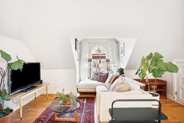 living area featuring lofted ceiling, baseboards, and light wood-type flooring