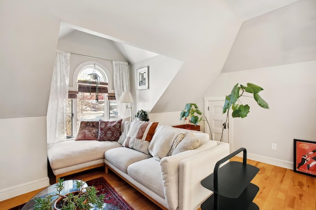 living area featuring baseboards, wood finished floors, and vaulted ceiling