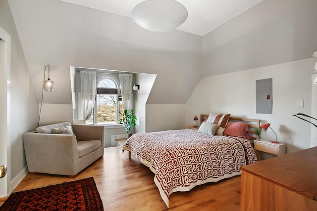 bedroom with electric panel, lofted ceiling, and wood finished floors