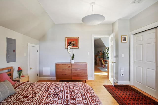 bedroom featuring baseboards, visible vents, lofted ceiling, electric panel, and light wood-style floors