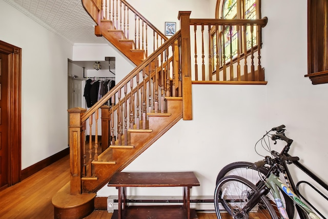 stairs featuring baseboards, wood finished floors, and crown molding