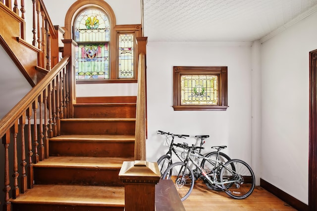 staircase with crown molding, baseboards, and wood finished floors