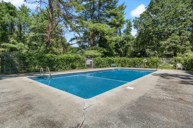 community pool with a patio area and fence