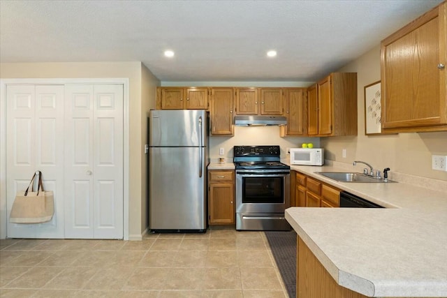 kitchen featuring a sink, light countertops, under cabinet range hood, and stainless steel appliances