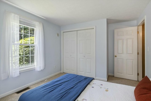 carpeted bedroom with visible vents, multiple windows, and baseboards