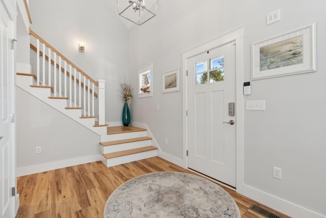 foyer entrance with stairs, visible vents, wood finished floors, and baseboards