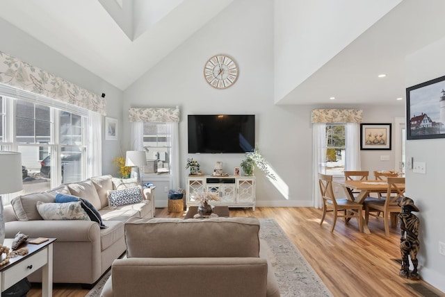 living area featuring visible vents, baseboards, light wood finished floors, high vaulted ceiling, and recessed lighting