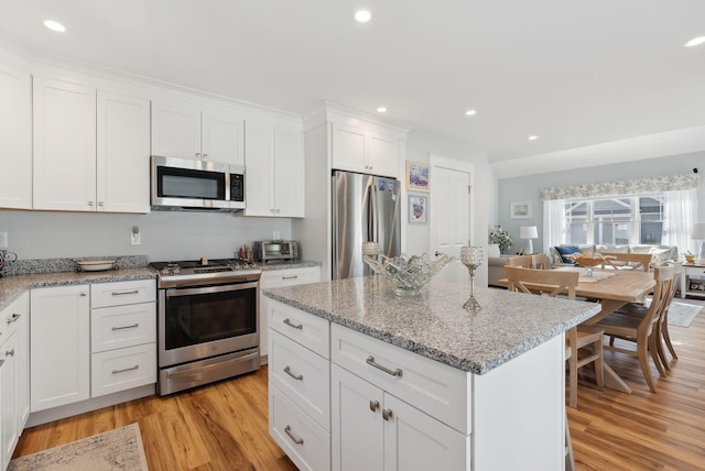 kitchen featuring a center island, white cabinetry, recessed lighting, stainless steel appliances, and light wood-style floors