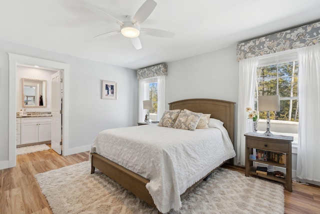 bedroom featuring connected bathroom, baseboards, ceiling fan, and light wood finished floors