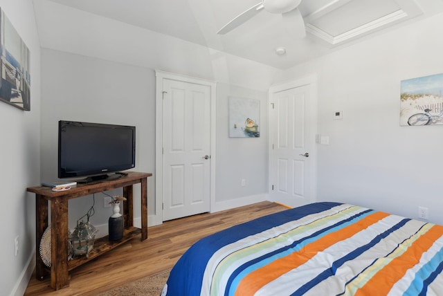 bedroom with attic access, a ceiling fan, baseboards, and wood finished floors