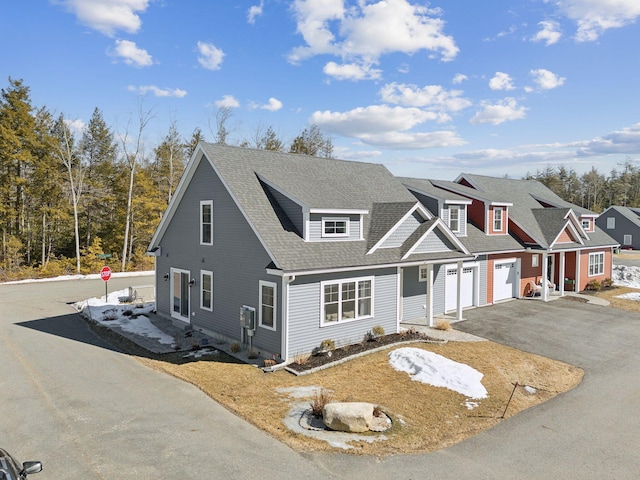 view of front of property with aphalt driveway, roof mounted solar panels, an attached garage, and roof with shingles