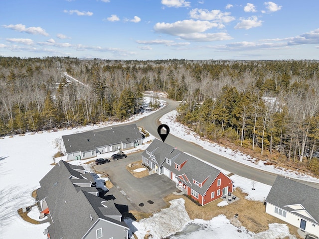 snowy aerial view featuring a wooded view