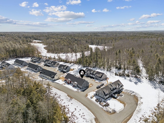 snowy aerial view featuring a wooded view