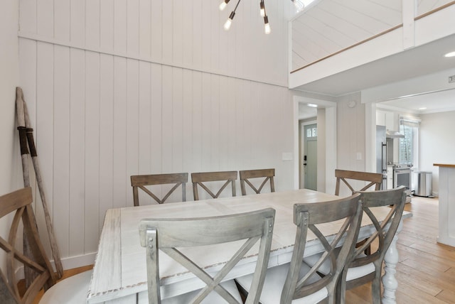 dining space featuring light wood-style flooring, baseboards, and an inviting chandelier