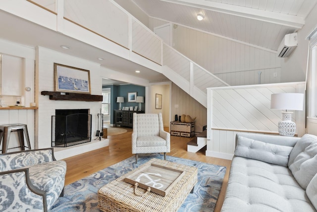 living room featuring a wall mounted air conditioner, beamed ceiling, high vaulted ceiling, wood finished floors, and a fireplace