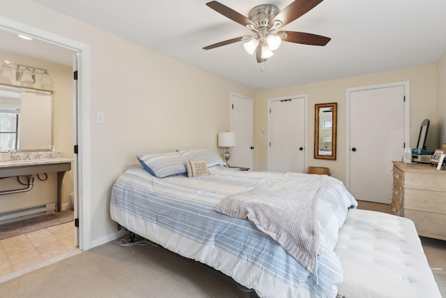 carpeted bedroom featuring two closets, ceiling fan, baseboards, ensuite bathroom, and a baseboard radiator