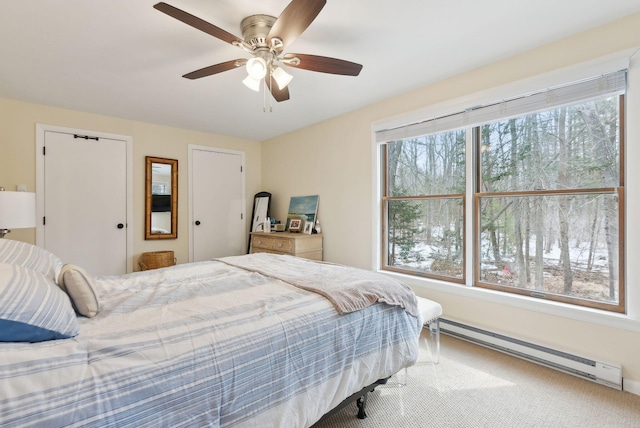 bedroom with a baseboard heating unit, multiple windows, ceiling fan, and carpet flooring