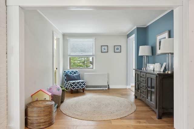 sitting room with wood finished floors, baseboards, and ornamental molding