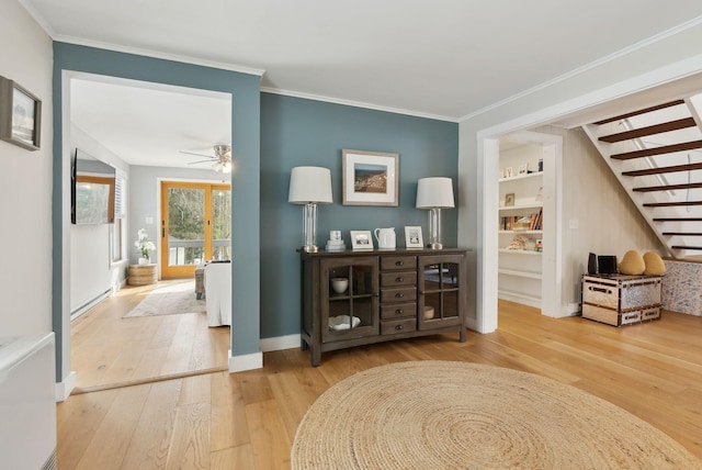 hallway featuring built in features, baseboards, ornamental molding, stairs, and wood-type flooring