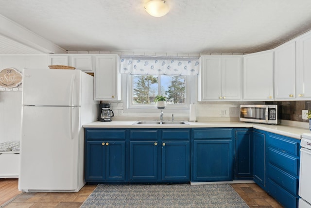 35 Grove Ave, Old Orchard Beach, ME 04064 - kitchen with tasteful backsplash, stainless steel microwave, blue cabinetry, freestanding refrigerator, and a sink