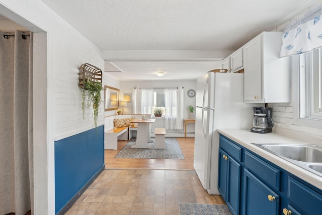 35 Grove Ave, Old Orchard Beach, ME 04064 - kitchen with light countertops, decorative backsplash, freestanding refrigerator, white cabinets, and blue cabinets