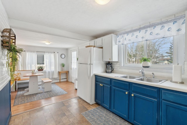 35 Grove Ave, Old Orchard Beach, ME 04064 - kitchen with blue cabinetry, freestanding refrigerator, a sink, light countertops, and a baseboard heating unit