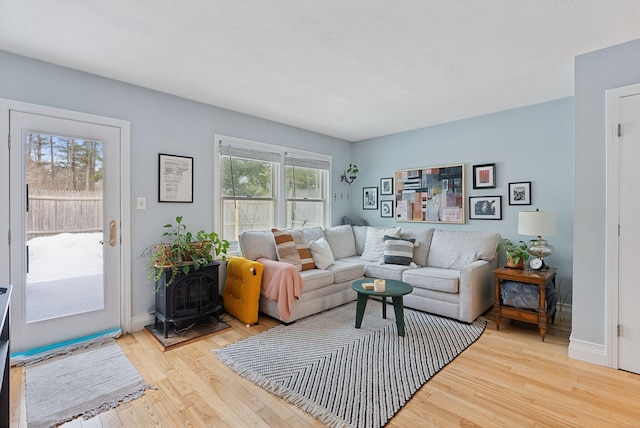 living room with a wood stove, baseboards, and wood finished floors