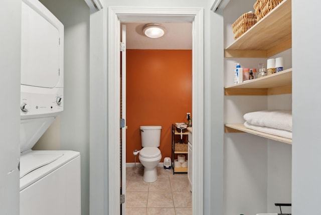 laundry room featuring light tile patterned floors, baseboards, stacked washer and dryer, and laundry area