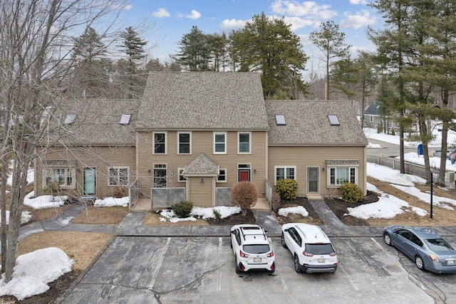 colonial-style house featuring uncovered parking and a shingled roof