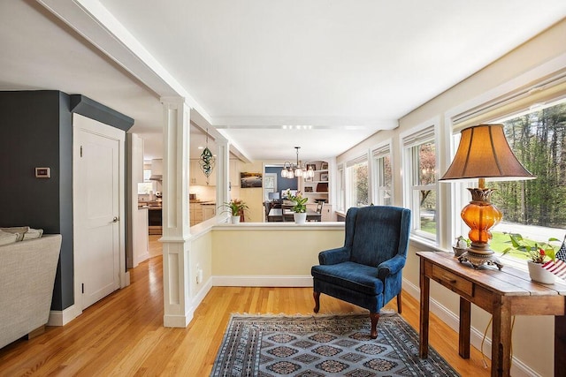 101 Whites Bridge Rd, Windham, ME 04062 - living area with decorative columns, light wood-type flooring, baseboards, and a chandelier