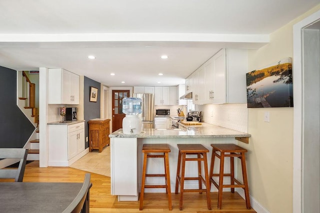 101 Whites Bridge Rd, Windham, ME 04062 - kitchen featuring appliances with stainless steel finishes, a peninsula, white cabinetry, a kitchen breakfast bar, and recessed lighting