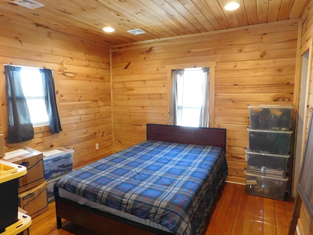 bedroom with visible vents, wood walls, wood ceiling, and hardwood / wood-style flooring